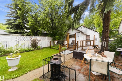Expansive backyard featuring a stone patio, manicured lawn, and white picket fence - 12016 61 Street, Edmonton, AB 