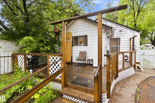 Exterior white siding residence featuring a wooden deck with railing, lattice accents, a ramp, and steps - 12016 61 Street, Edmonton, AB 