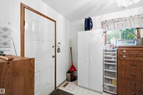 White paneled entry door with wood-finish trim, complemented by white walls and a window with wood-finish casing - 12016 61 Street, Edmonton, AB 