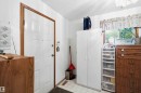 White paneled entry door with wood-finish trim, complemented by white walls and a window with wood-finish casing - 12016 61 Street, Edmonton, AB 