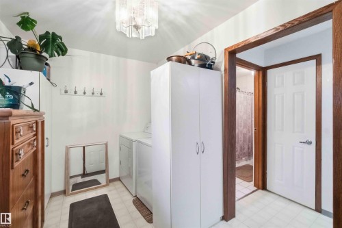 Utility space featuring tile flooring, white walls, and a multi-paneled door with wood trim - 12016 61 Street, Edmonton, AB 