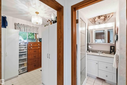 Bathroom featuring a vanity with white cabinetry, a light-colored countertop, and a mirrored medicine cabinet - 12016 61 Street, Edmonton, AB 