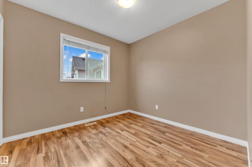 Neutral wall paint and wood-finish flooring define this space, illuminated by a window with white blinds - 1328 80 Street, Edmonton, AB 