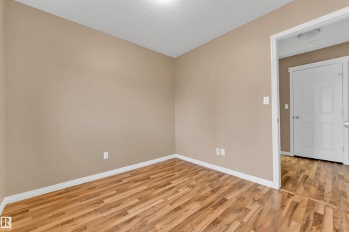 Neutral-toned interior room with wood-finish flooring, white baseboards, and a white ceiling - 1328 80 Street, Edmonton, AB 