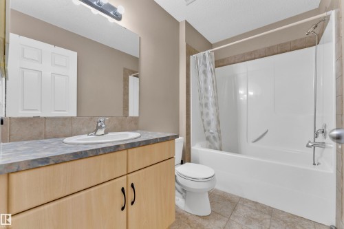 Full bathroom featuring a light wood-finish vanity with a laminate countertop, ceramic tile backsplash, and an integrated sink - 1328 80 Street, Edmonton, AB 