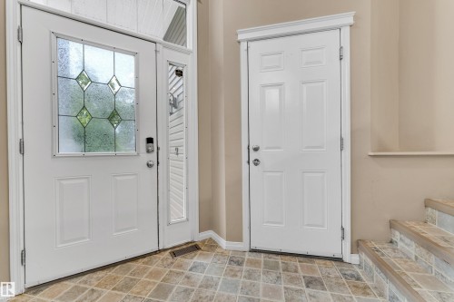 Entryway featuring a decorative glass panel door, an adjacent side light, a tiled floor, and a second panel door with a crown molding header - 1328 80 Street, Edmonton, AB 