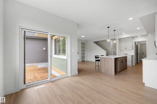 Open concept living space featuring wood-finish flooring, a kitchen island with seating, pendant lighting, and recessed ceiling lights - 24 Grayson Green, Stony Plain, AB 