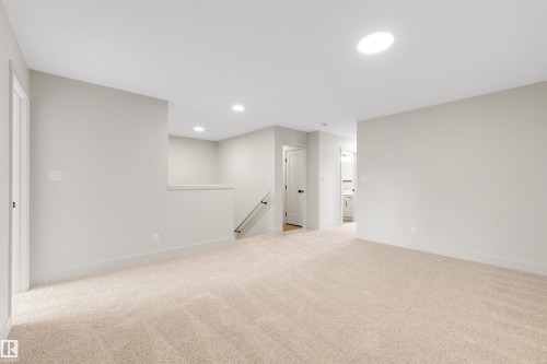 Spacious carpeted room featuring recessed lighting, a skylight, light grey walls, white trim, and doors with matte black hardware - 24 Grayson Green, Stony Plain, AB 