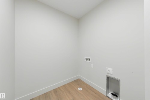 Dedicated laundry area featuring light wood-finish flooring, white baseboards, and neutral wall paint - 24 Grayson Green, Stony Plain, AB 