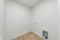 Dedicated laundry area featuring light wood-finish flooring, white baseboards, and neutral wall paint - 