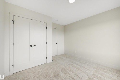 Neutral-toned room featuring a light-colored carpet, white walls, and a white ceiling with a flush-mount light fixture - 24 Grayson Green, Stony Plain, AB 