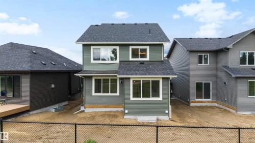 Rear exterior featuring green horizontal siding, white trim, multiple windows across two levels, and a dark shingled roof - 24 Grayson Green, Stony Plain, AB 