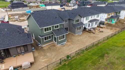 Rear exterior featuring green siding, dark shingle roofing, multiple windows, and a foundation - 24 Grayson Green, Stony Plain, AB 