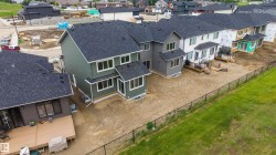 Rear exterior featuring green siding, dark shingle roofing, multiple windows, and a foundation - 