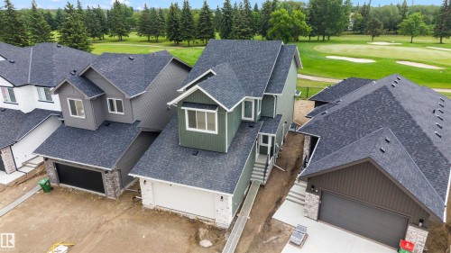 Newly constructed home featuring a dark green exterior, attached garage, and a steeply pitched shingle roof - 24 Grayson Green, Stony Plain, AB 