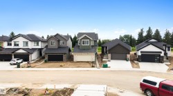 Modern residences featuring dark roofing, attached garages, and a mix of exterior siding and stone accents - 