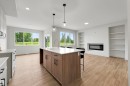 Open-concept living area featuring a kitchen island with built-in cabinetry, quartz countertops, and a stainless steel sink - 24 Grayson Green, Stony Plain, AB 