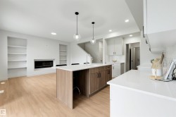 Open-concept living space featuring a central island with wood-finish cabinetry, white countertops, and pendant lighting - 