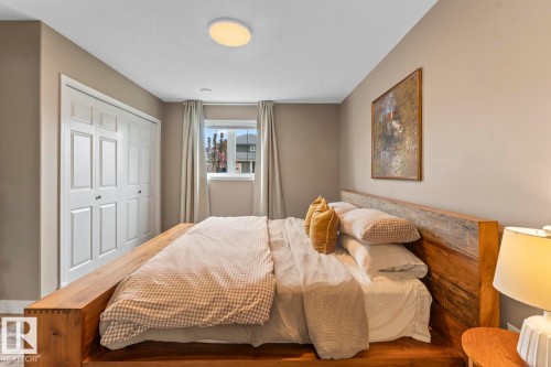 Bedroom featuring a large window with soft drapes, closet with bifold panel doors, and neutral wall tones - 2602 Delta Road, Cold Lake, AB 