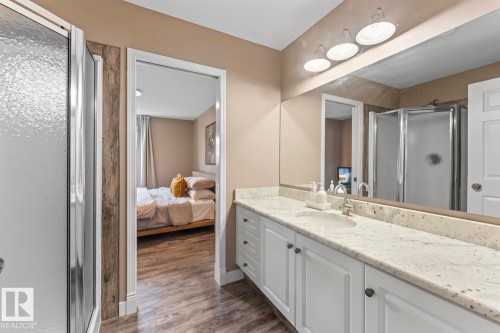 Bathroom vanity with an integrated sink and light-toned countertop, featuring white cabinetry and a large wall-mounted mirror - 2602 Delta Road, Cold Lake, AB 