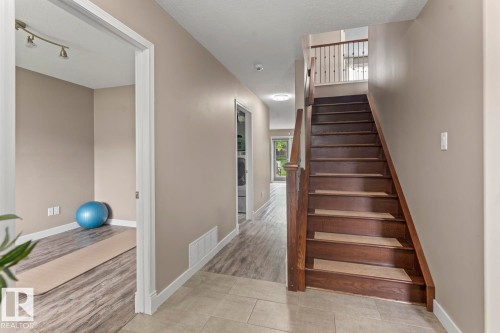 Wood-finish staircase with carpeted treads, a dark wood handrail, and wrought iron balusters - 2602 Delta Road, Cold Lake, AB 