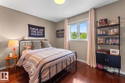 Warm-toned wood-finish flooring complements neutral wall paint in this room featuring a window with white trim, a semi-flush mount ceiling light fixture, and a built-in shelving unit with lower cabinetry - 2602 Delta Road, Cold Lake, AB 