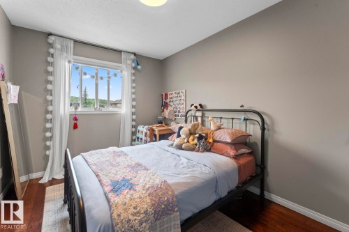 Bedroom featuring dark wood-finish flooring, neutral wall paint, and a large window - 2602 Delta Road, Cold Lake, AB 