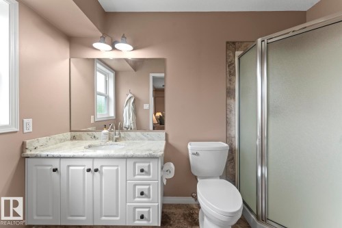 Bathroom featuring a white vanity with panel doors, a light-toned countertop, and a rectangular mirror - 2602 Delta Road, Cold Lake, AB 