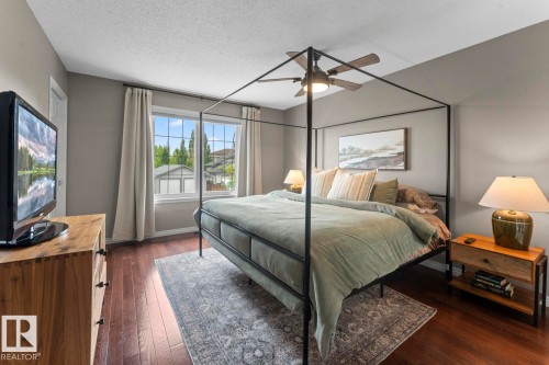 Spacious bedroom featuring rich wood-finish flooring, a ceiling fan with integrated lighting, and multiple windows with white trim - 2602 Delta Road, Cold Lake, AB 