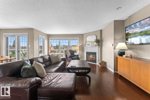 Spacious living area featuring wood-finish flooring, a white mantel fireplace, and ample natural light from multiple windows - 2602 Delta Road, Cold Lake, AB 