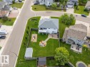 Rear exterior featuring a large green lawn, a ground-level patio, an elevated deck, and a detached shed - 2602 Delta Road, Cold Lake, AB 