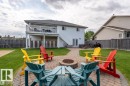 Expansive backyard featuring a circular paver patio with fire pit, surrounding lawn, and a multi-level deck with white railing - 2602 Delta Road, Cold Lake, AB 