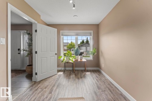 Open concept space featuring wood-finish flooring, neutral paint tones, and a large window with white blinds - 2602 Delta Road, Cold Lake, AB 
