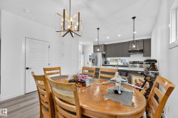 Dining area with wood-finish flooring and a contemporary chandelier - 