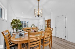 Dining area featuring wood-finish flooring, a modern linear chandelier, recessed lighting, and a white paneled door with matte black hardware - 