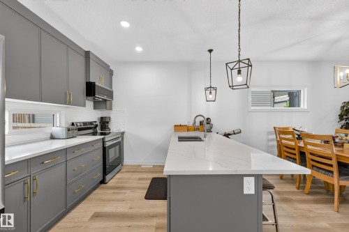 Modern kitchen featuring shaker-style cabinetry with gold-tone hardware, stainless steel appliances, white subway tile backsplash, and light wood-finish flooring - 104 Kidd Crescent, Leduc, AB 