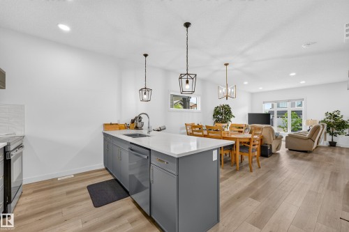 Modern kitchen island featuring a white countertop, undermount sink with gooseneck faucet, and gray cabinetry - 104 Kidd Crescent, Leduc, AB 