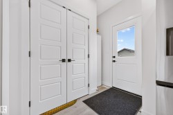 Entryway featuring a white paneled door with integrated glass, complemented by light wood-finish flooring - 