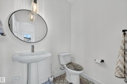 Pedestal sink with a wall-mounted round mirror and contemporary pendant lighting - 