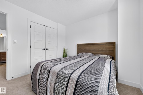 Bedroom featuring light-colored carpet, white walls, and a wood-finish headboard - 104 Kidd Crescent, Leduc, AB 