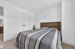 Bedroom featuring light-colored carpet, white walls, and a wood-finish headboard - 