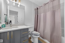 Bathroom featuring a single vanity with gray cabinetry, gold-toned hardware, and a white countertop - 