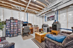 Unfinished basement featuring exposed ceiling joists, insulated walls, and a recessed window - 