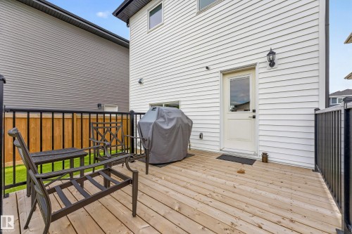 Expansive wooden deck featuring black metal railings and a rear exterior door - 104 Kidd Crescent, Leduc, AB 