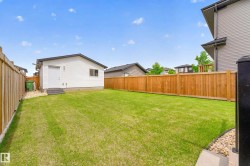 Spacious backyard featuring a detached accessory structure with a side entry door and single window, full wood perimeter fencing, a manicured lawn, and a small gravel area - 