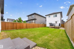 Expansive backyard featuring a manicured lawn, a wooden fence, and a rear deck with black railings - 