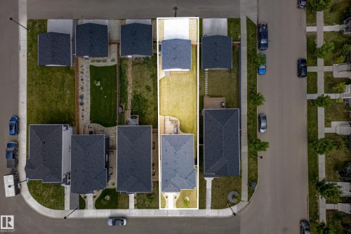 Overhead view of a residential property featuring a dark-shingled roof, a light-toned driveway, and a spacious green lawn - 104 Kidd Crescent, Leduc, AB 