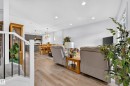 Open-concept living space featuring wood-finish flooring, recessed lighting, and a white baluster staircase - 104 Kidd Crescent, Leduc, AB 