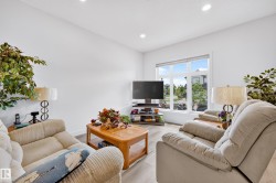 Spacious living area featuring bright white walls, recessed ceiling lighting, a large window, and wood-finish flooring - 