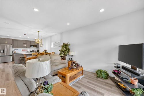Open-concept living space featuring wood-finish flooring, recessed lighting, and a neutral color palette - 104 Kidd Crescent, Leduc, AB 